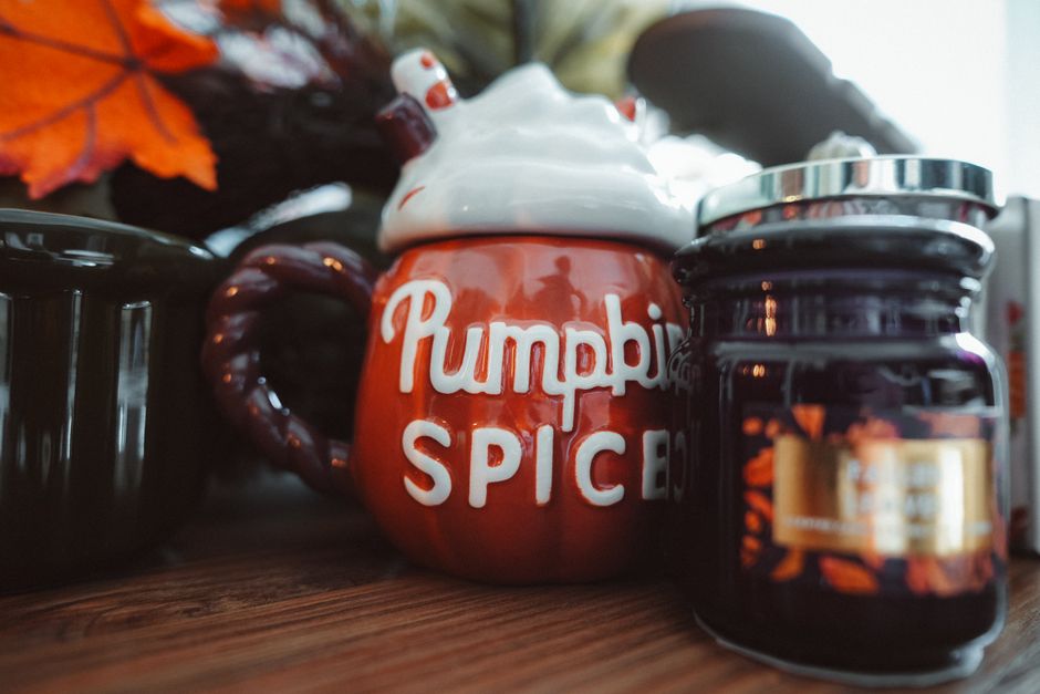 Rustic autumn setup featuring a pumpkin spice mug and candle for cozy home decor.