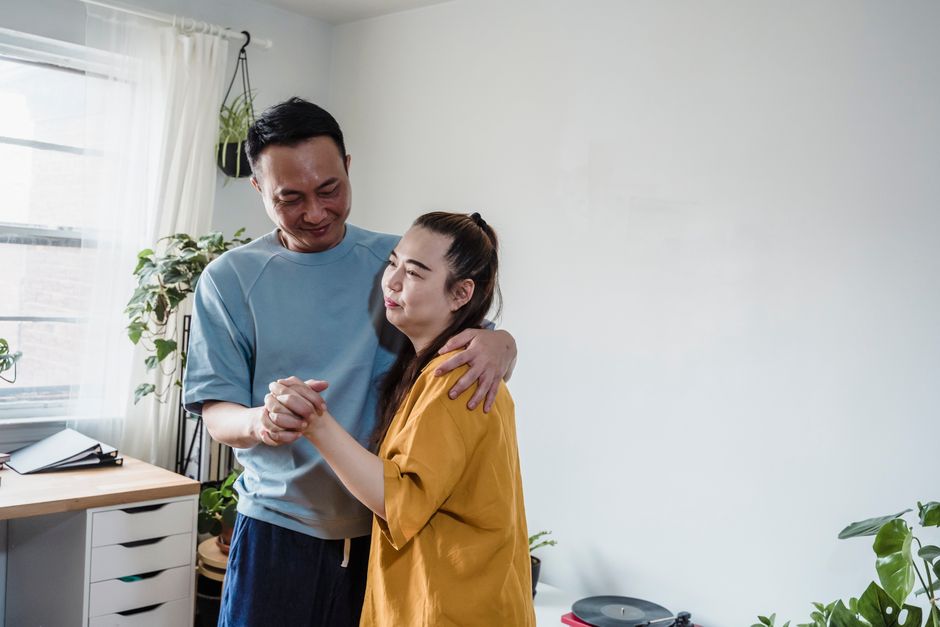 Couple sharing a tender moment and dancing together in a bright, plant-filled living room.